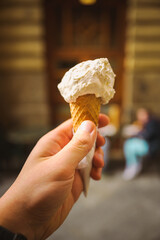 A close up shot of an italian artisanal ice cream cone and a hand holding it.