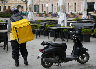 food delivery courier delivers food in city, town. Delivery courier motor scooter with yellow...