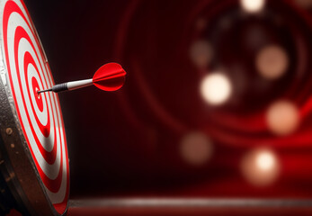 A red dart is stuck in the center of a red and white bullseye target on  the bokeh effect background. Concept of achieving successful plan goal achievement in business
