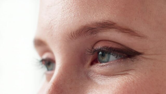 Blinking, eyes and lashes for health of vision, closeup and sight for looking in white background. Studio, person and adult with cosmetics of microblading of eyebrow on face with care for beauty