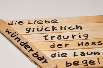 close up of a hand written german words on  popsicle sticks as a self esteem building concept, emotion, love, happy, sad, exited, hate, mood, activities.