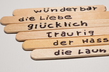 close up of a hand written german words on  popsicle sticks as a self esteem building concept,...