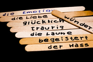 close up of a hand written german words on  popsicle sticks as a self esteem building concept, emotion, love, happy, sad, exited, hate, mood, activities.