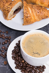 White cup of coffee and fresh croissant with chocolate