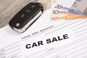 Car key, euro banknotes and vehicle sales agreement. Inscription car sale. Sales and buying new or used car