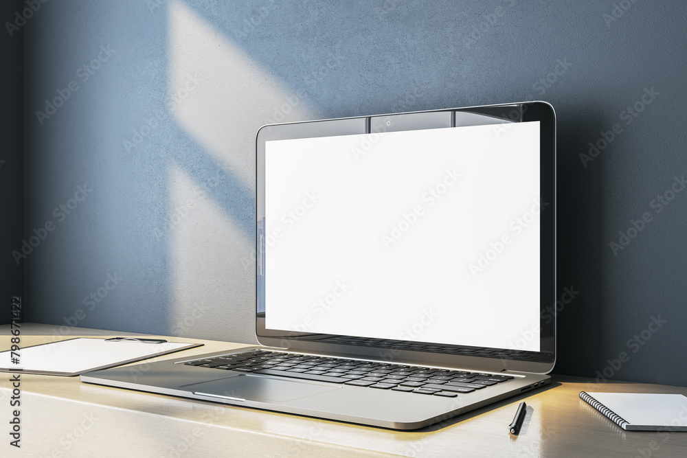 Poster close up of empty white computer screen on simple wooden desk. blue wall background. workplace conce