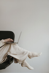 Young woman in beige clothes works using laptop computer over white wall. Aesthetic neutral pastel...