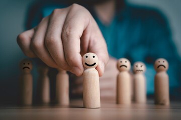 Businessman pushing smile wooden figure in front of sad figure for positive mindset and excellent quality customer evaluation survey after use product and service concept.