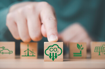 Hand pushing CO2 reducing icon in front of environment icon for decrease CO2 , carbon footprint and carbon credit to limit global warming from climate change, Bio Circular Green Economy concept.