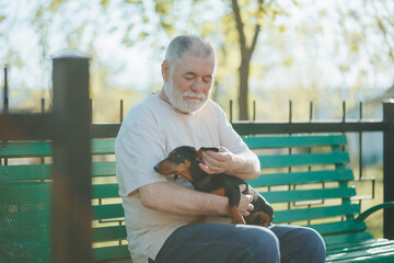 Man's Comfort Senior Gentleman Relaxes in the Park with His Trusty Dachshund