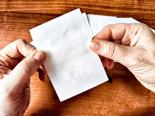 Obraz premium Woman Holding Small White Papers Over a Wooden Surface. Hands presenting several small white papers