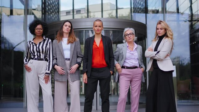 Zoom camera. Group of empowered diverse business women in formal suit standing with arms crossed posing confident together. Proud and successful adult females entrepreneurs co-workers outdoor