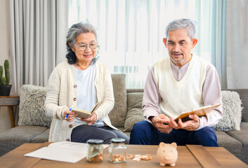 asian senior couple is looking for savings plan together,old man holding money savings chart,his wife holding note book,concept of money management in elderly people,savings