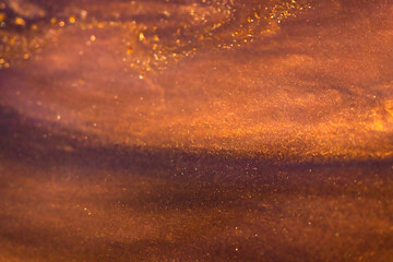 Liquid paint abstract background. Red and golden acrylic paints with shimmering golden glitter 