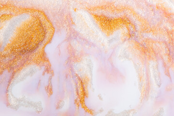 Colorful liquid paint abstract background. Pink and white acrylic paints with golden glitter 