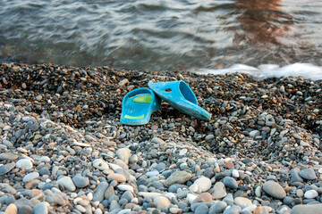 Two slippers forgotten on the beach. Beach slippers on the pebble shore. Two slippers were left on...