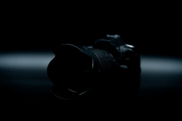 old DSLR photo camera at black background from side close up low key