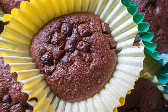 Homemade baked chocolate cupcake with chocolate chips sitting inside colorful baking liner inside closeup