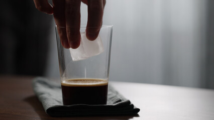 man making iced coffee with espresso coffee in glass on wood table