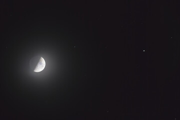 The mineral Moon in its first quarter phase, in conjunction with the star Pollux in the Gemini constellation and some background stars. You can see the earth-shine in the shadowed part.