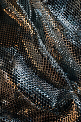 Textured surface of metallic mesh, featuring interwoven strands and reflective properties. Metallic mesh textures offer a modern and industrial backdrop