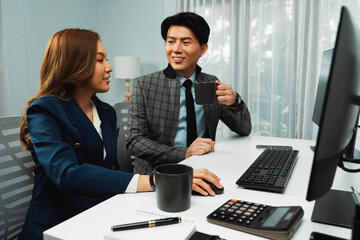 Smiling Asian man discussing marketing project while holding coffee cup with woman colleague...