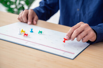 Businessman manages time for effective work. Calendar on table . Embroidered  pins appointment reminders and meeting agenda on the calendar. Time management concept .