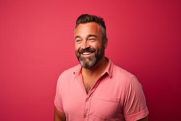 Fototapeta premium Portrait of a happy mature man with beard and mustache on a pink background