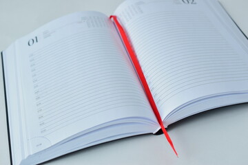 Open notebook. Blank white sheets, red bookmark.