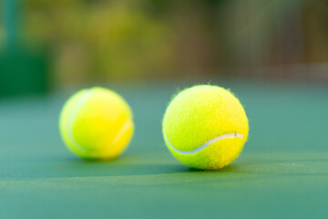 tennis balls on green hard court with soft shadow