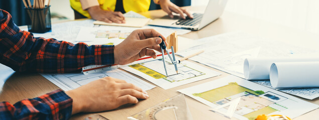 Cropped image of professional engineer team working on blueprint while his coworker working on...