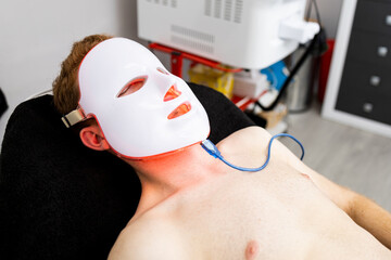 LED mask! An unrecognizable man undergoes therapy with an LED mask with red light to repair damaged...