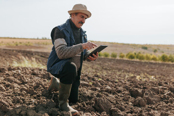 Digital Harvest Insights Senior Farmer Analyzing Soil with Tablet
