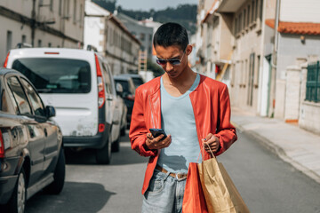 young man with shopping bags and phone on the street