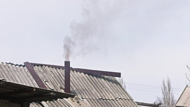 Black smoke coming out from rustic bathhouse chimney steel pipe, the concept of heating with low quality coal or rags.