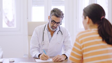 Doctor talking with a woman while writing down notes