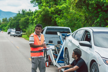 Car tow agent man giving towing paper to owner man for moving breakdown vehicle on roadside