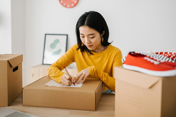 Young entrepreneur asian woman preparing packages for delivering to customer. E-commerce and delivery service concept.