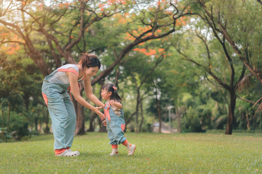 Asian mother walking with daughter in park, Happy family in the park evening light, Happy family concept.
