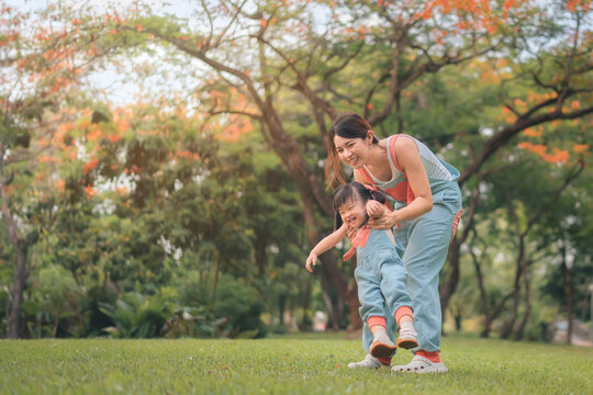 Asian mother walking with daughter in park, Happy family in the park evening light, Happy family concept.