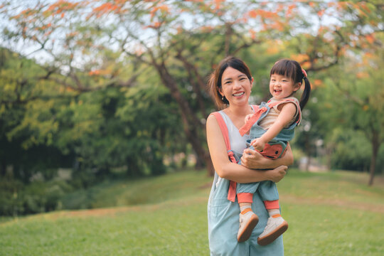 Asian mother walking with daughter in park, Parents hold the baby's in his hand , Happy family in the park evening light. Happy family concept.