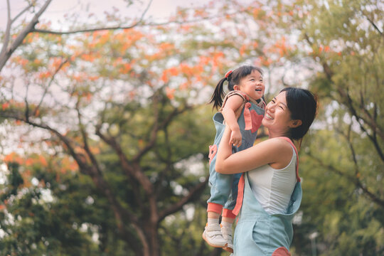 Asian mother walking with daughter in park, Parents hold the baby's in his hand , Happy family in the park evening light, Happy family concept.