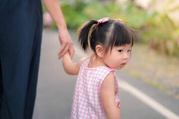 Asian mother walking with daughter in park, Parents hold the baby's hands, Happy family in the park...