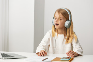 Smiling girl using laptop for elearning at home, enjoying online education She sits at a desk with...