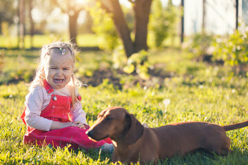 crying little girl with her dachshund dog in the summer garden