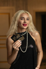 Portrait of a young beautiful blonde girl in a black dress in the studio.
