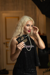 Portrait of a young beautiful blonde girl in a black dress in the studio.