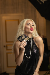 Portrait of a young beautiful blonde girl in a black dress in the studio.