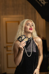 Portrait of a young beautiful blonde girl in a black dress in the studio.