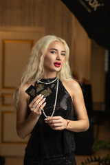 Portrait of a young beautiful blonde girl in a black dress in the studio.